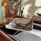 Silver dish on top of a Chanel book with a mirror and cacti in the background