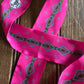 Pink ribbon scarf with geometric pattern on a wooden surface