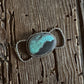Silver twilly slide with a turquoise stone on a wooden surface