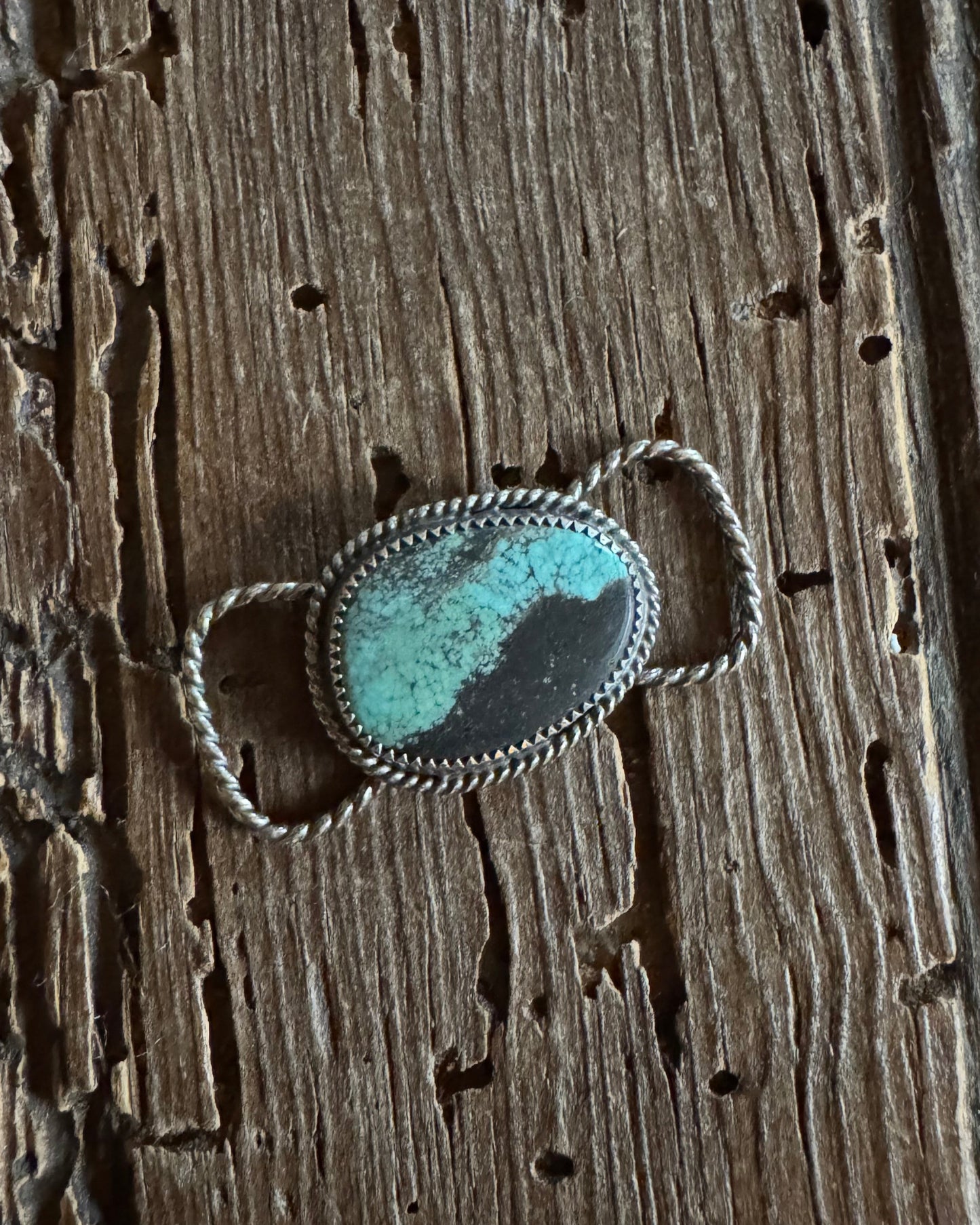 Silver twilly slide with a turquoise stone on a wooden surface
