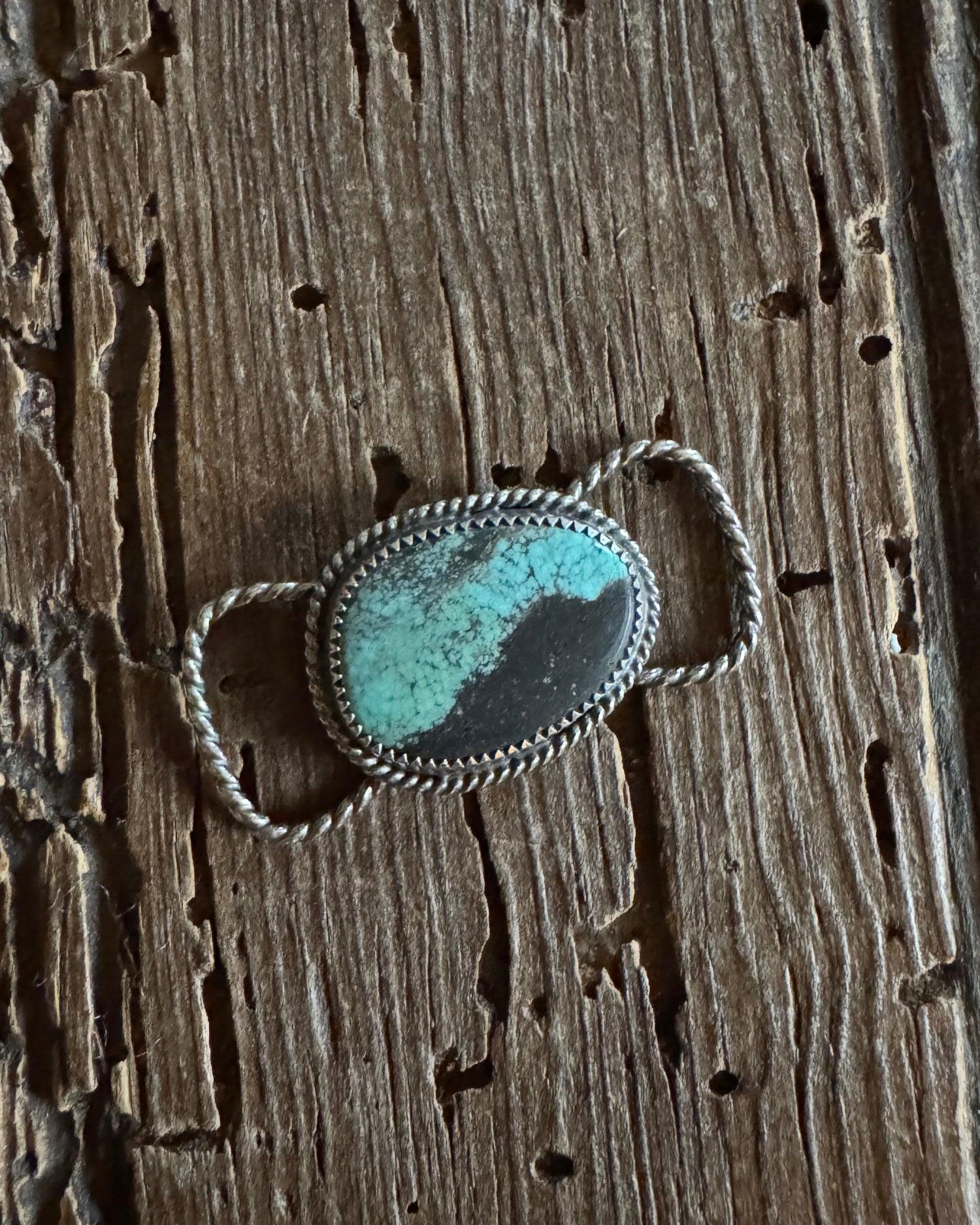 Silver twilly slide with a turquoise stone on a wooden surface