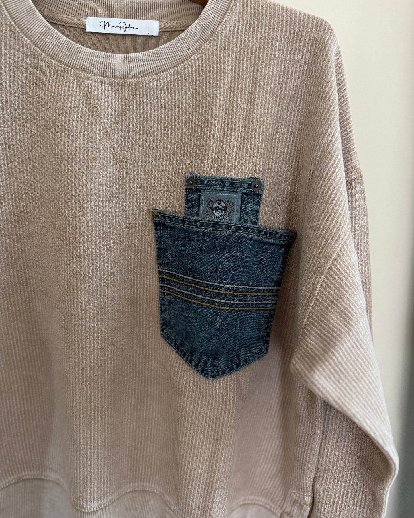 Beige corduroy shirt with denim pocket on a hanger