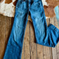 Blue jeans on a wooden floor with a cowhide rug in the background