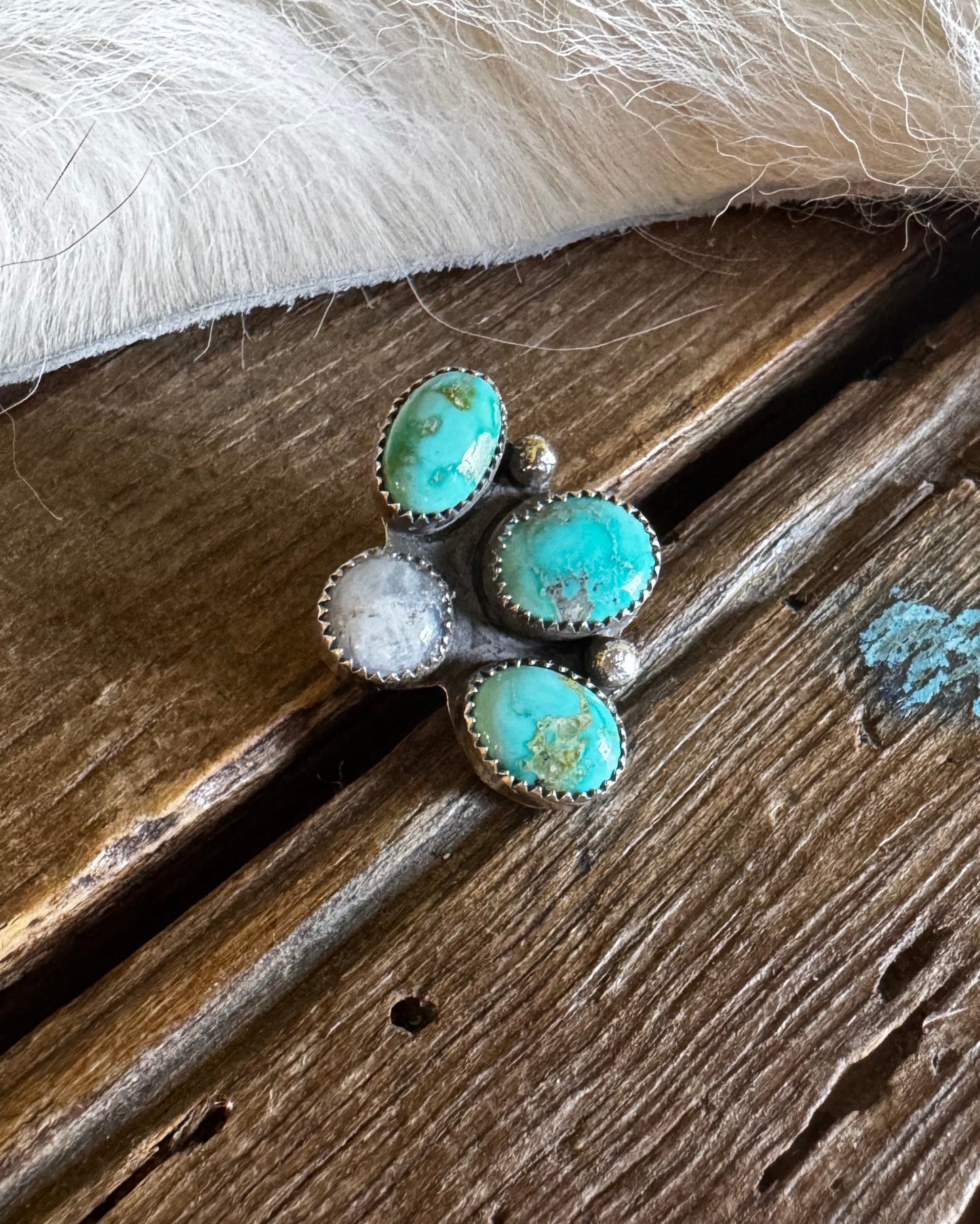 Turquoise stone ring on a wooden surface with white fur
