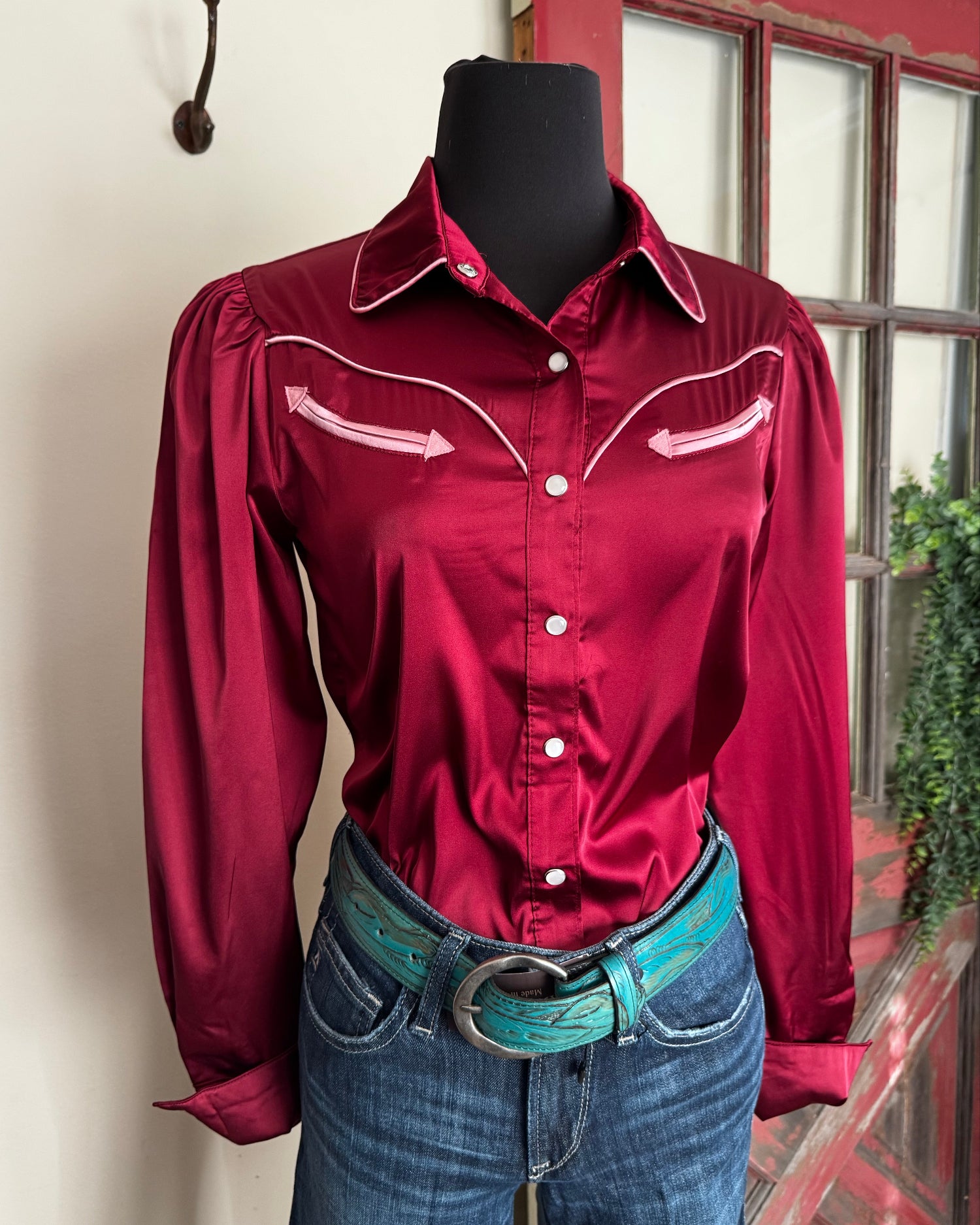 Red shirt and blue jeans hanging on a rack indoors.