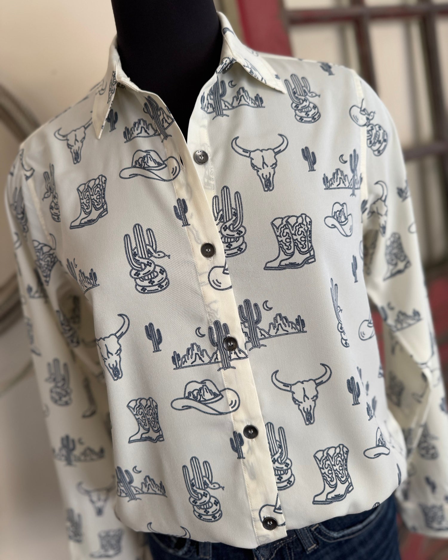 White shirt with blue western-themed pattern on a mannequin against a neutral background