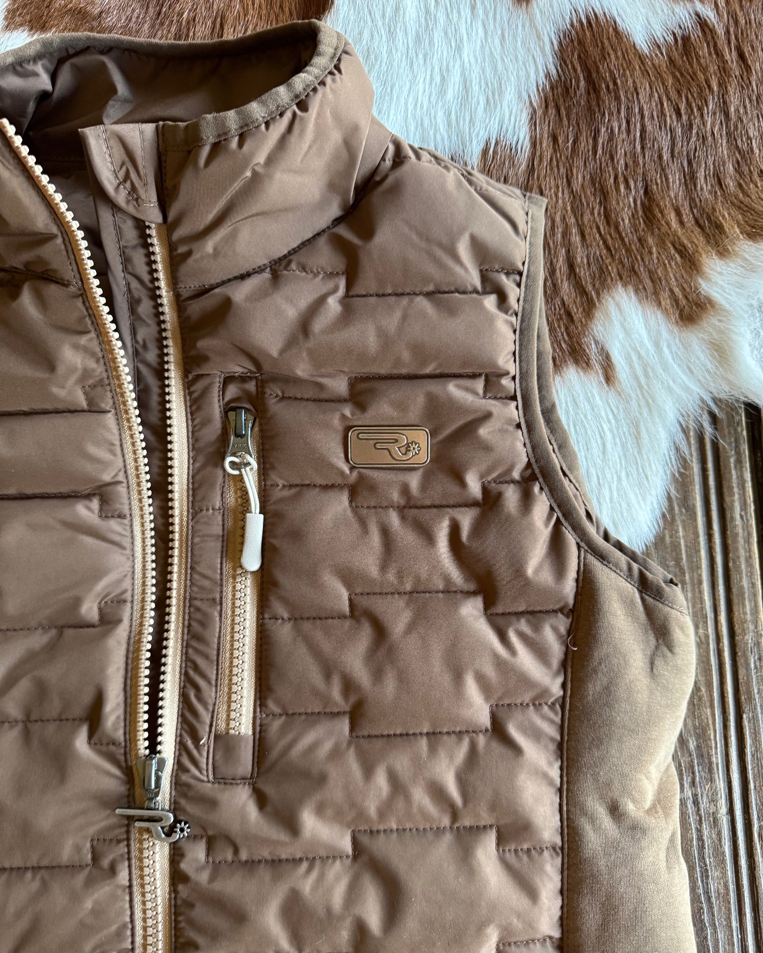 Brown quilted jacket with a visible brand logo on a wooden surface.