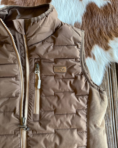 Brown quilted jacket with a visible brand logo on a wooden surface.