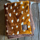 Folded brown blanket with white spots on a wooden surface
