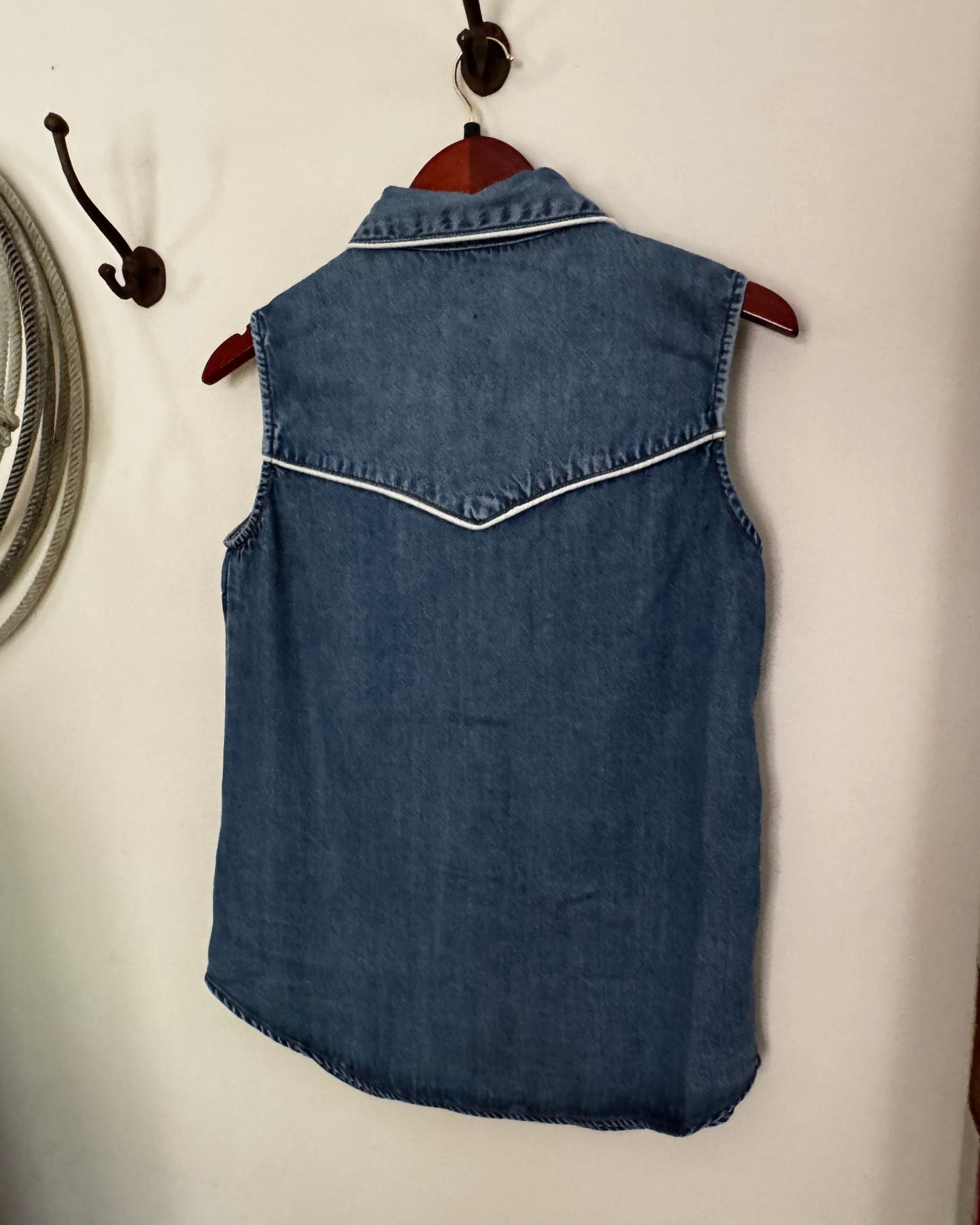 Blue denim dress on a white surface with a mirror and red object in the background