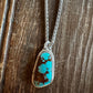 Turquoise stone pendant on a chain against a wooden background
