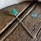 Turquoise stone pendant on a chain against a wooden surface