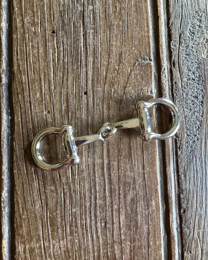 Silver snaffle bit on a wooden surface