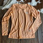 Beige t-shirt with logos on a wooden surface next to a cowhide rug