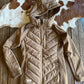 Beige quilted jacket on a wooden surface with cowhide rug