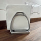 Metal stirrup on a white paper towel with a wooden surface and white wall in the background