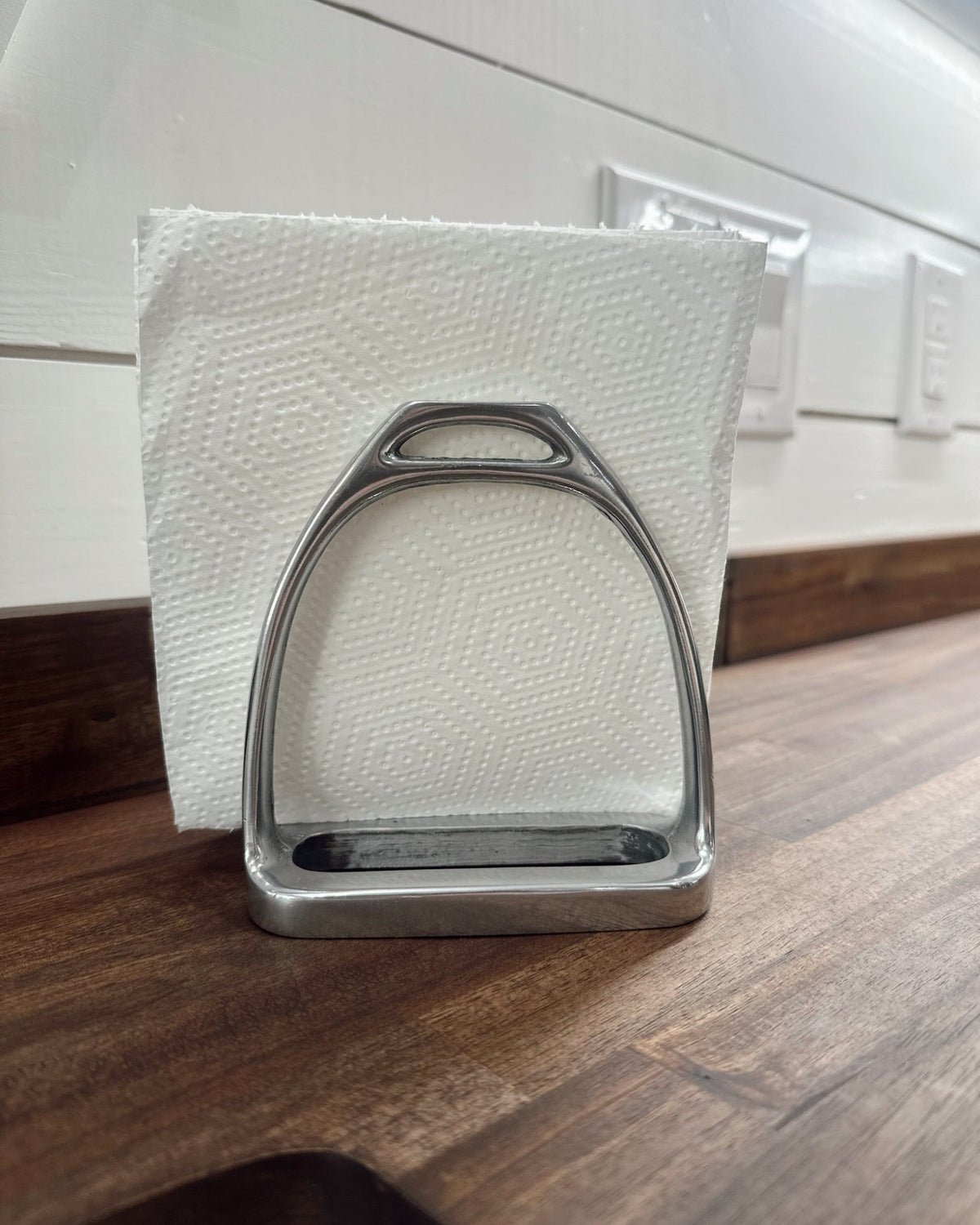 Metal stirrup on a white paper towel with a wooden surface and white wall in the background