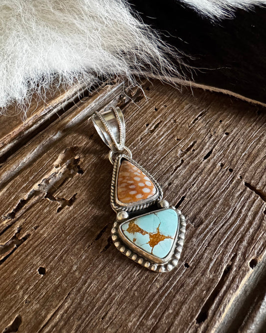 Turquoise stone pendant on a wooden surface with fur in the background
