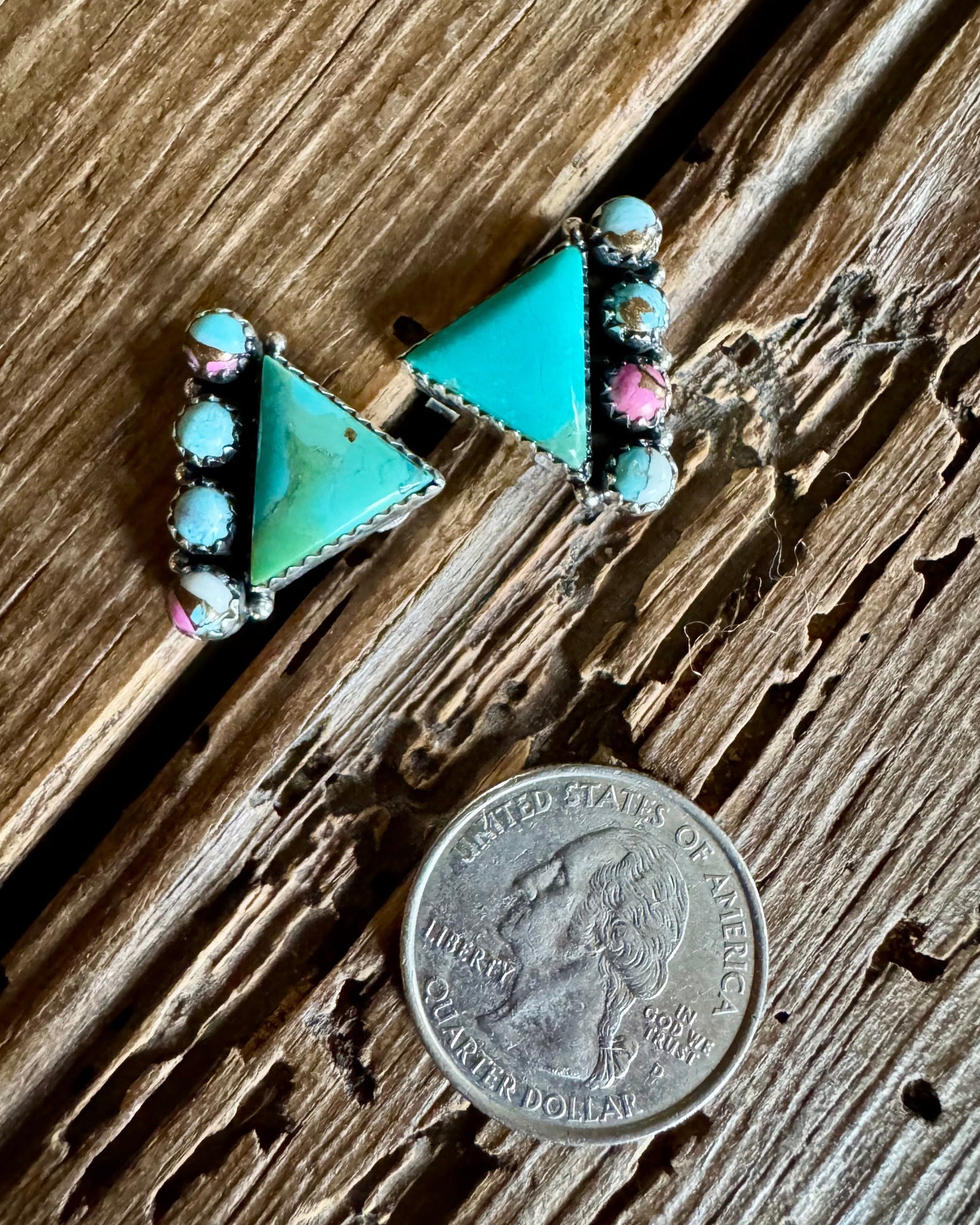 Turquoise triangle-shaped earrings on a wooden surface with a quarter for scale.