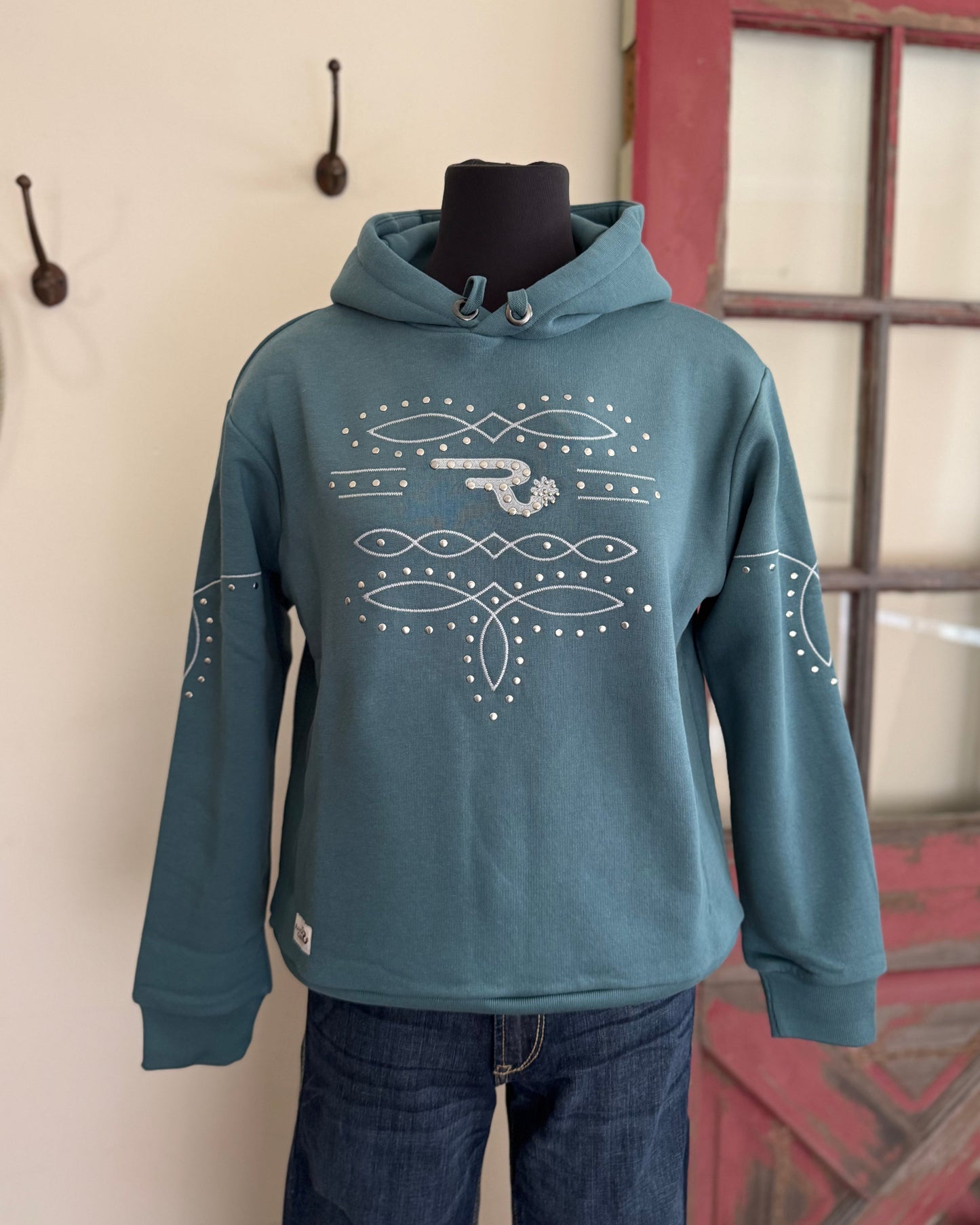 Blue hoodie with white patterns on a mannequin against a neutral wall.