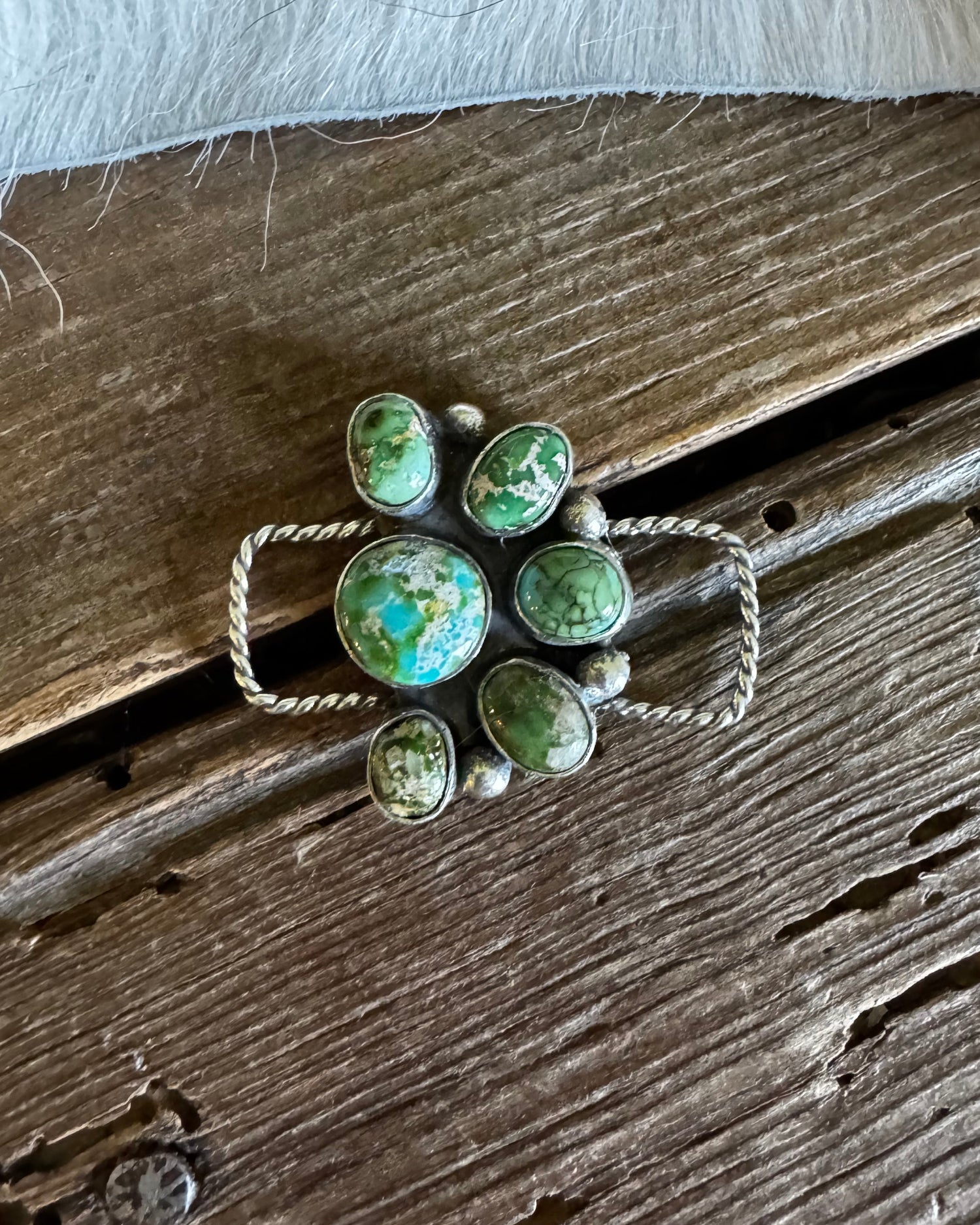 Jewelry with green stones and silver accents on a wooden surface