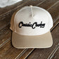Beige cap with 'Casual Cowboy' text on a wooden surface