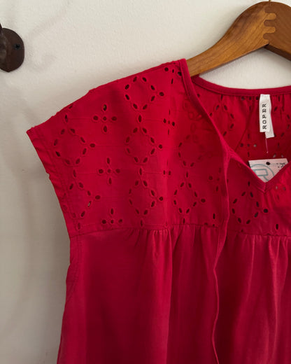 Red dress with cut-out details on a hanger against a white wall