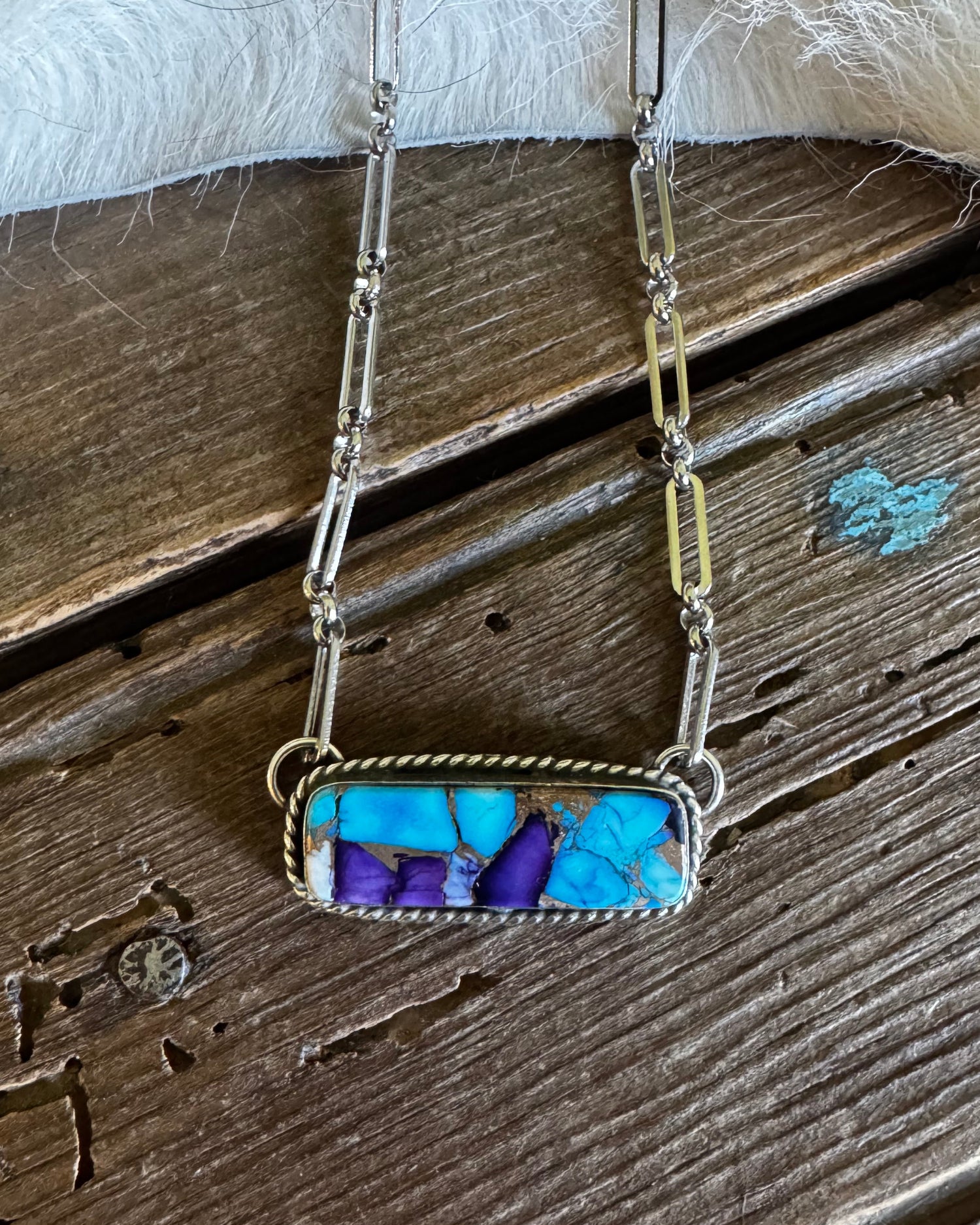 Necklace with a blue and purple stone on a wooden surface