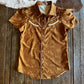 Brown patterned garment on a wooden surface next to a cowhide rug