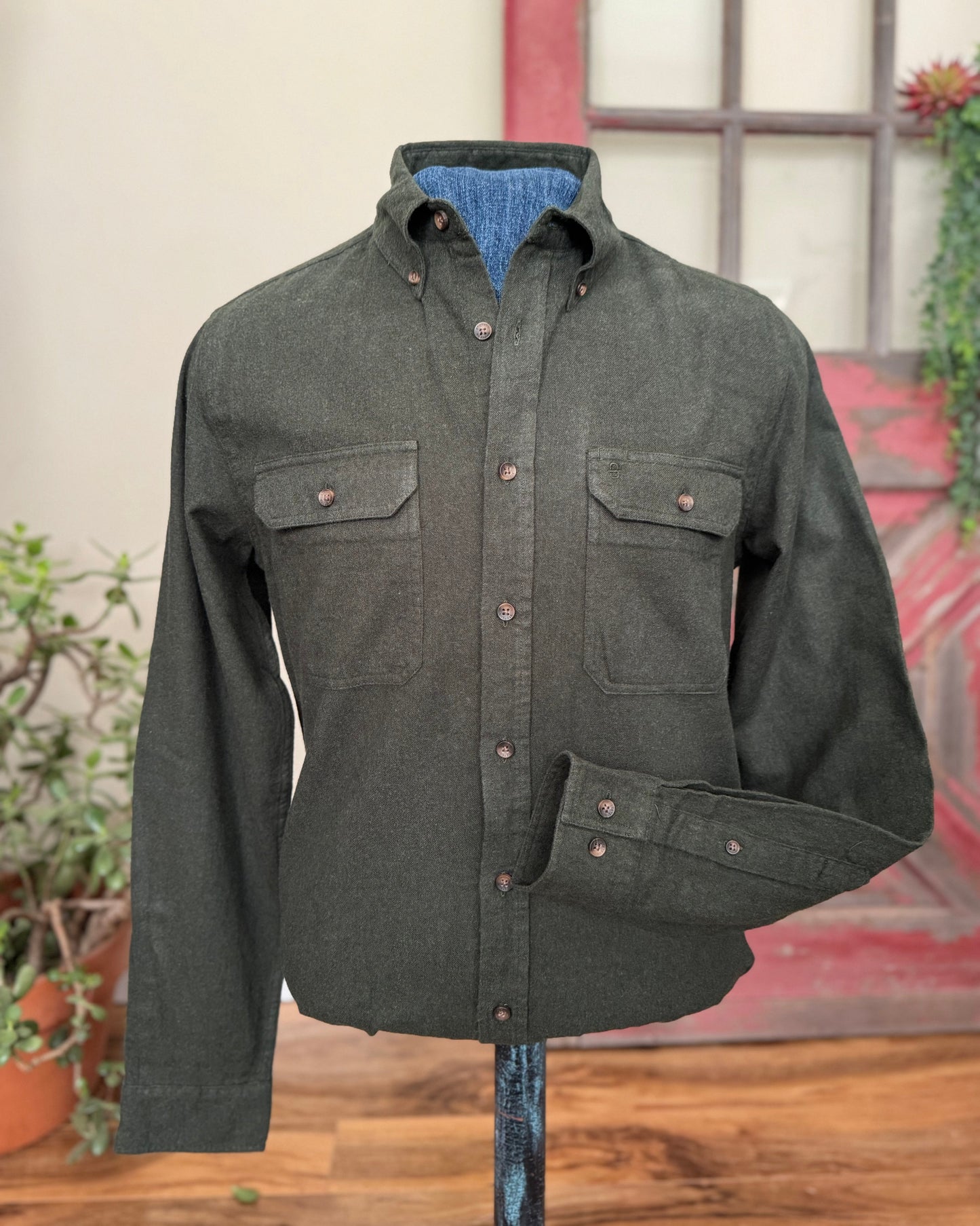 Olive green shirt on a stand against a neutral background