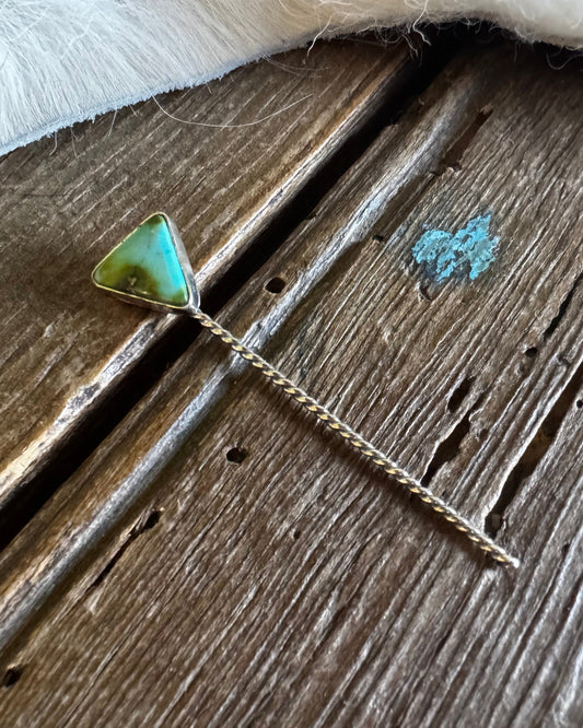Necklace with a green triangle pendant on a textured surface