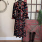 Floral dress on a mannequin with boots on a wooden floor against a rustic wall.