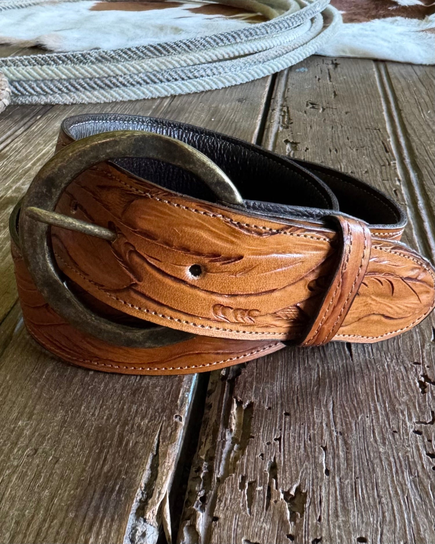 Brown leather belt with intricate designs on a wooden surface
