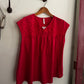 Red shirt on a hanger against a white wall