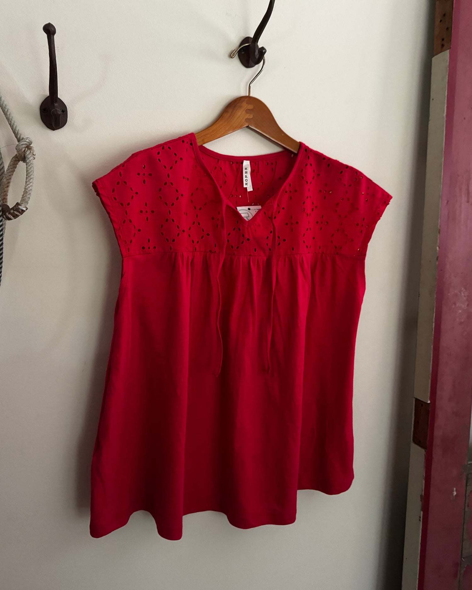 Red shirt on a hanger against a white wall