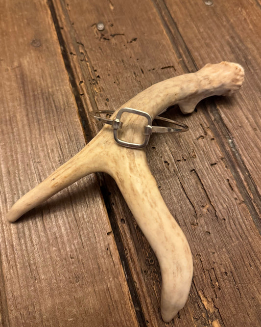 Antler with silver bracelet on a wooden surface