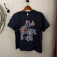 Navy blue t-shirt with graphic design on a wooden hanger against a white wall.