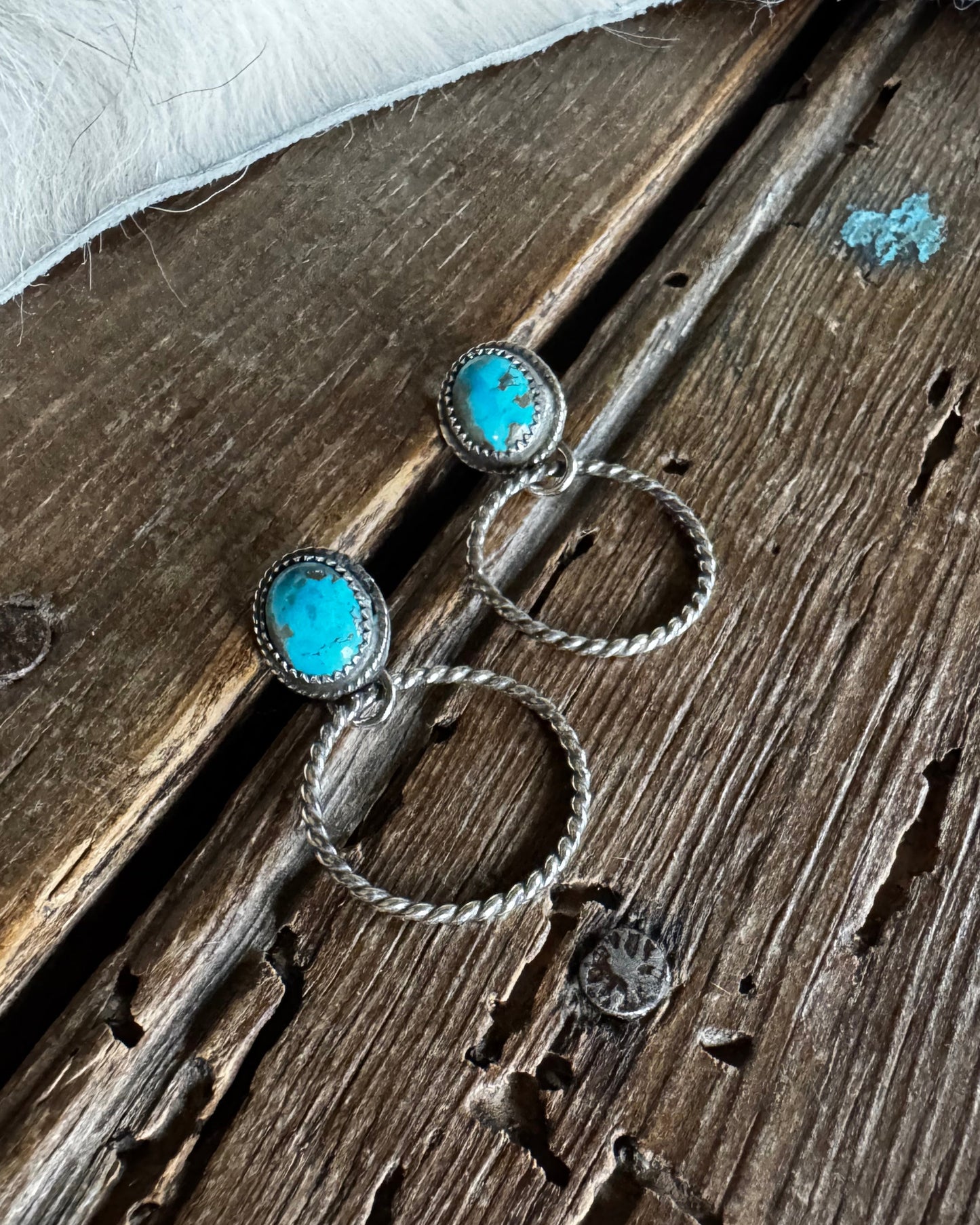 silver earrings with turquoise stones on a wooden surface
