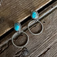 Pair of silver earrings with turquoise stones on a wooden surface