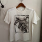 White t-shirt with horse graphic on a hanger against a white wall