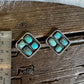 Pair of turquoise stone earrings on a wooden surface with a ruler for scale.