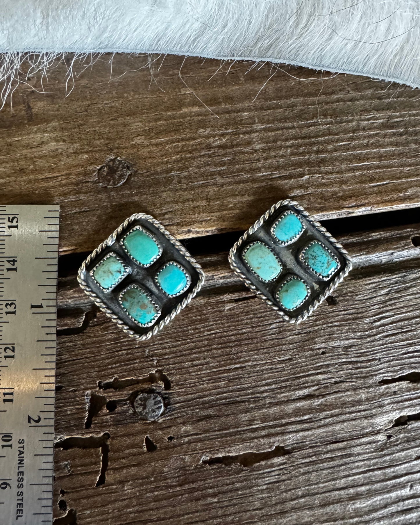 Pair of turquoise stone earrings on a wooden surface with a ruler for scale.