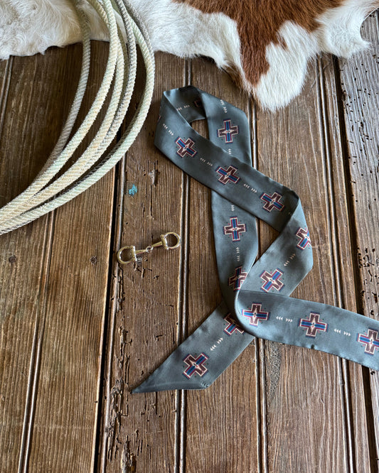 sage patterned scarf on a wooden surface with cowhide leather and rope.