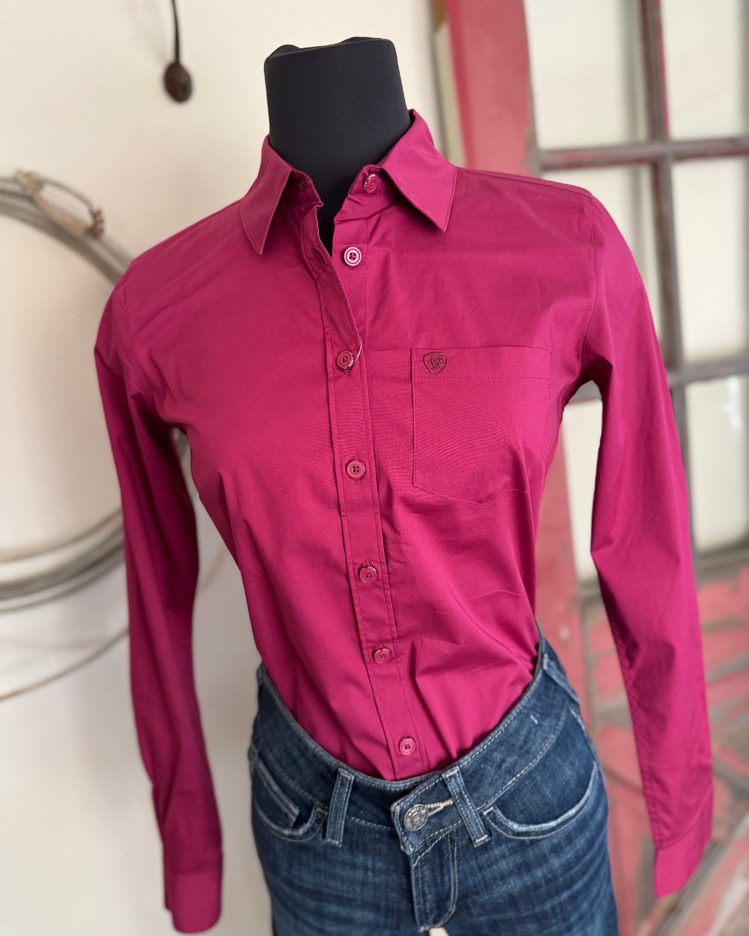 Mannequin wearing a pink shirt and blue jeans against a neutral background