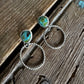 Pair of earrings with turquoise stones on a wooden surface