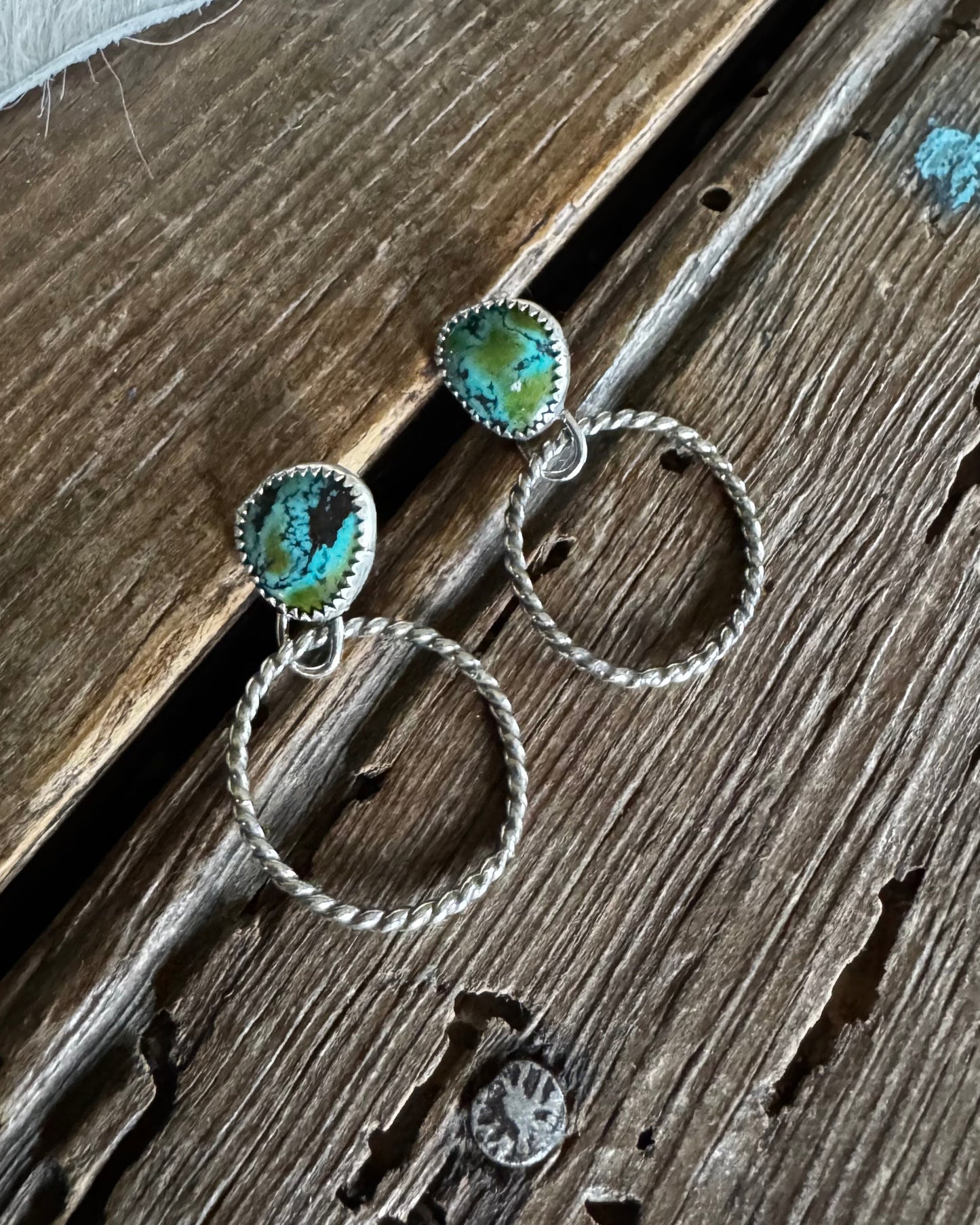 Pair of earrings with turquoise stones on a wooden surface