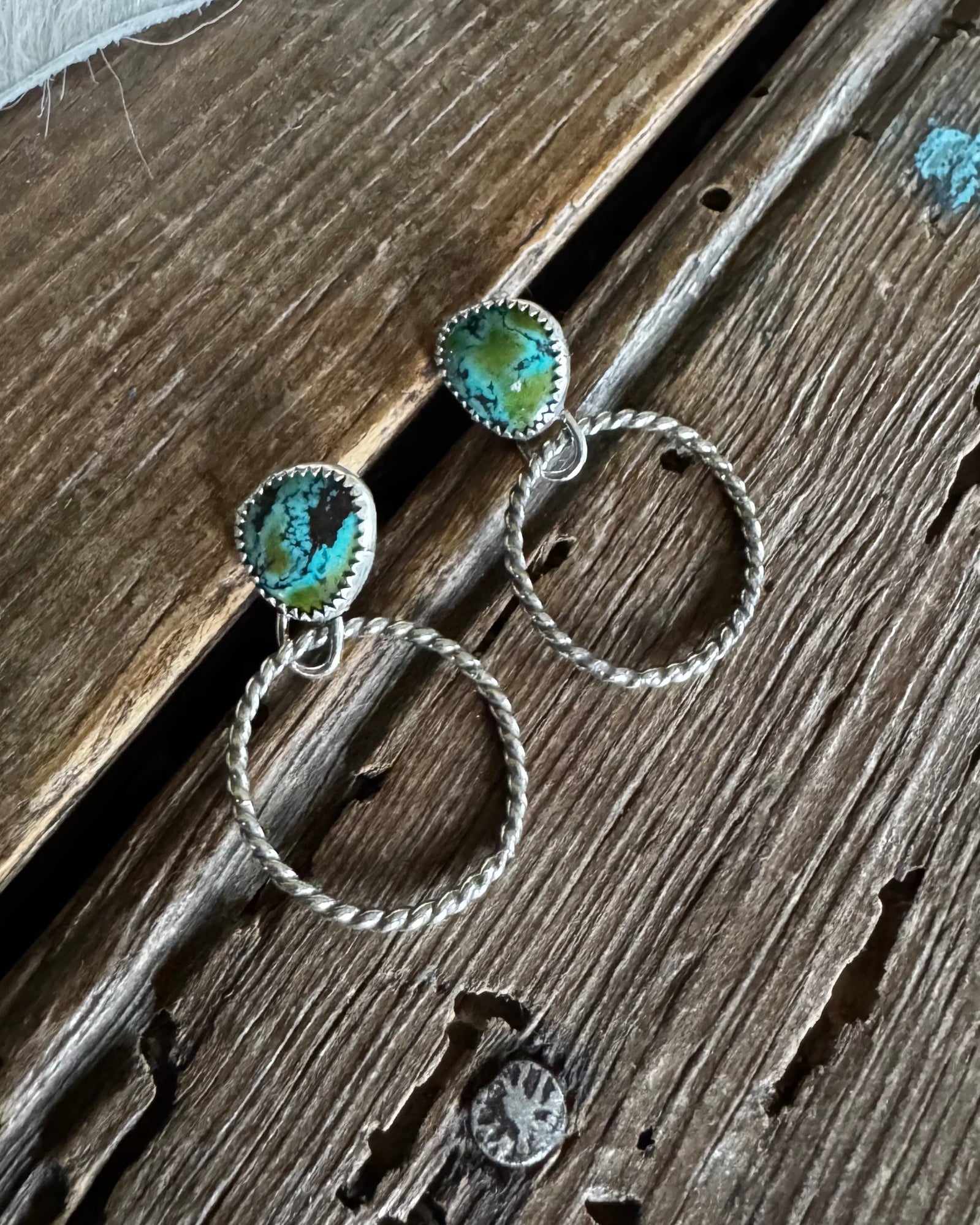 Pair of earrings with turquoise stones on a wooden surface