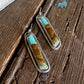 Pair of earrings with turquoise and gold stones on a wooden surface