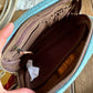 Open blue and brown pouch with a hand holding it, on a wooden surface.