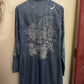 Blue denim shirt with white graphics on a beige wall
